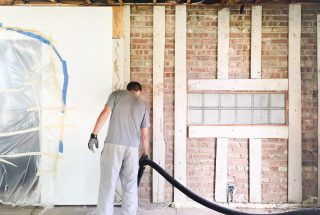 man-vacuums-with-long-shop-vac-hose-in-renovation--GZ5UR9A